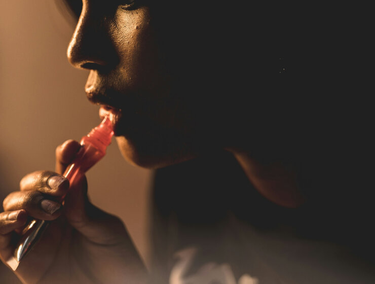 Black woman applying lip gloss via unsplash