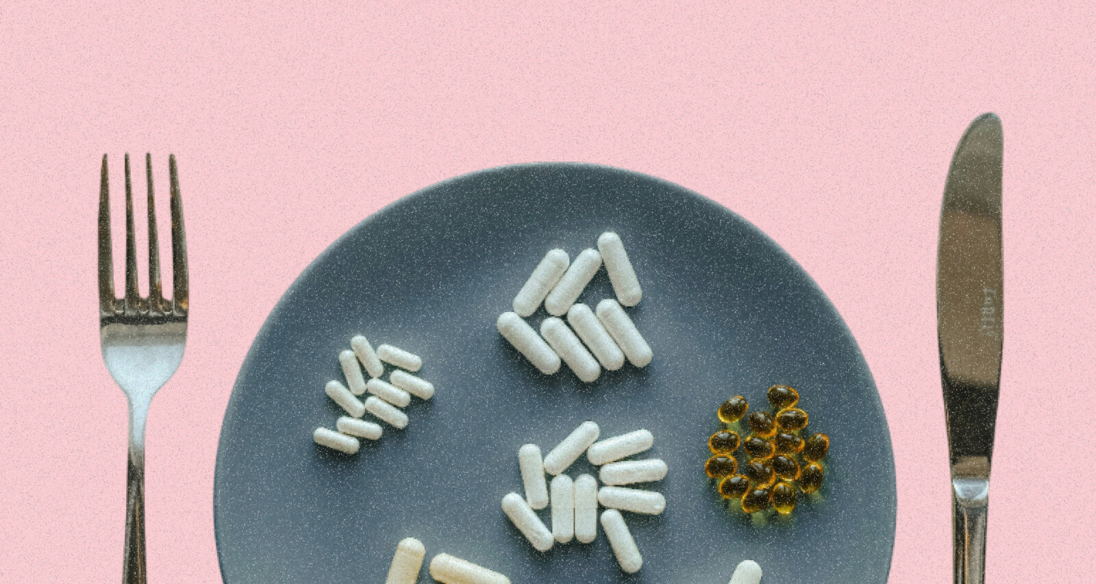 A plate containing a spread of supplements, flanked on either side by a knife and fork via Unsplash