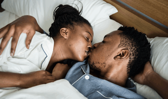 A couple kssing in bed via Freepik.