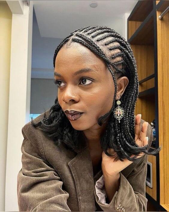 This image features a woman with a "babyface" attachment hairstyle. Her hair is styled in neat, medium-sized braids that frame her face elegantly. The braids are intricately patterned and styled to fall just above the shoulders, creating a refined and sophisticated look. This attachment hairstyle is perfect for those seeking a chic and polished appearance.